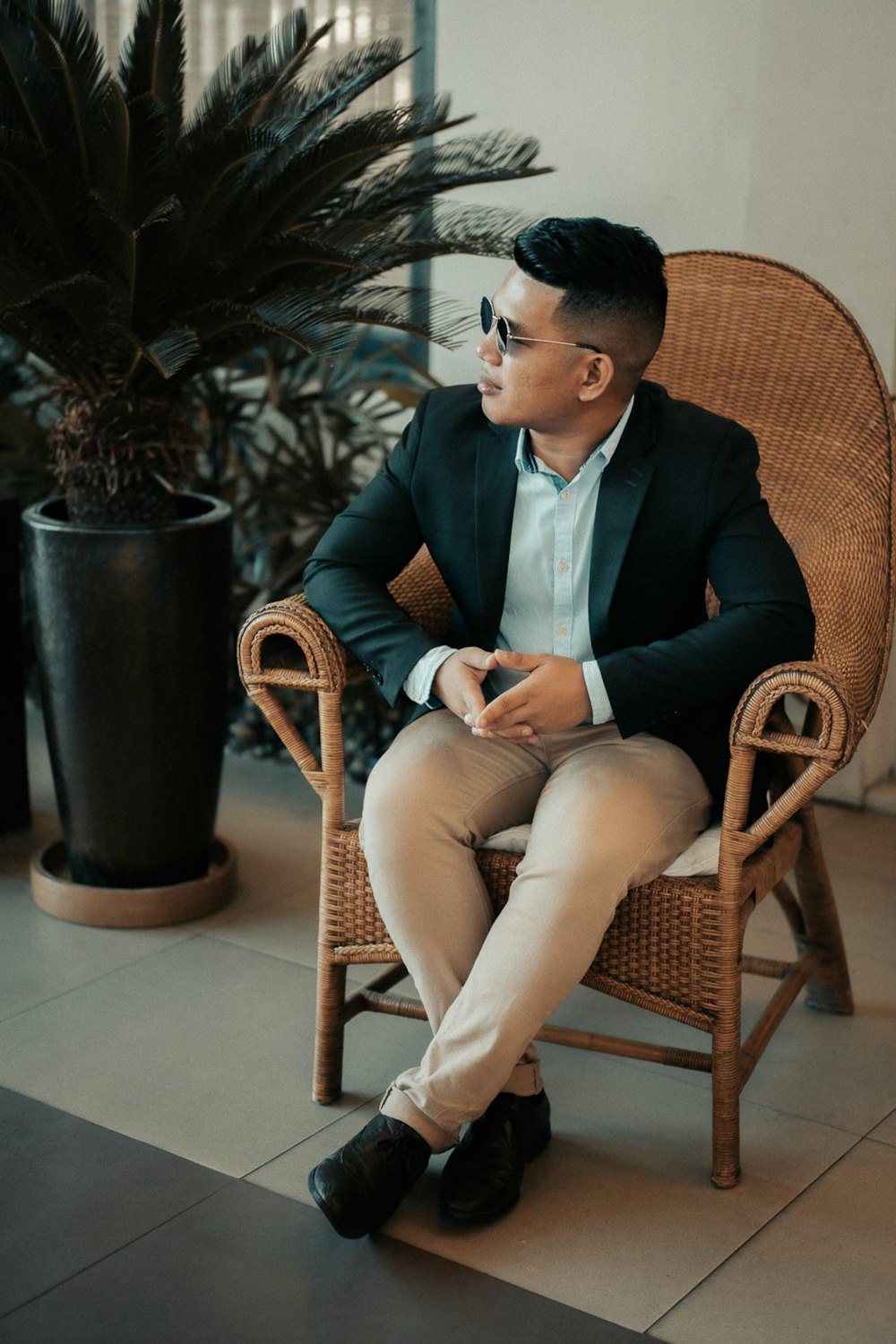 man in black suit sitting on brown wicker chair