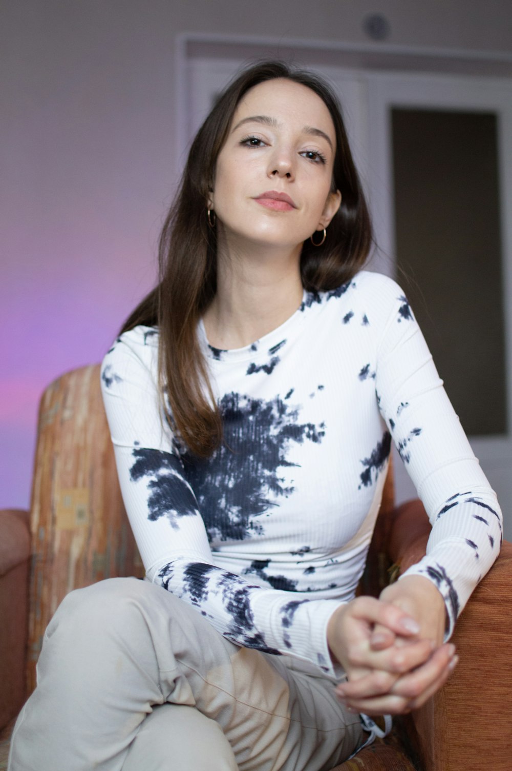 woman in white and black floral long sleeve shirt sitting on brown wooden chair