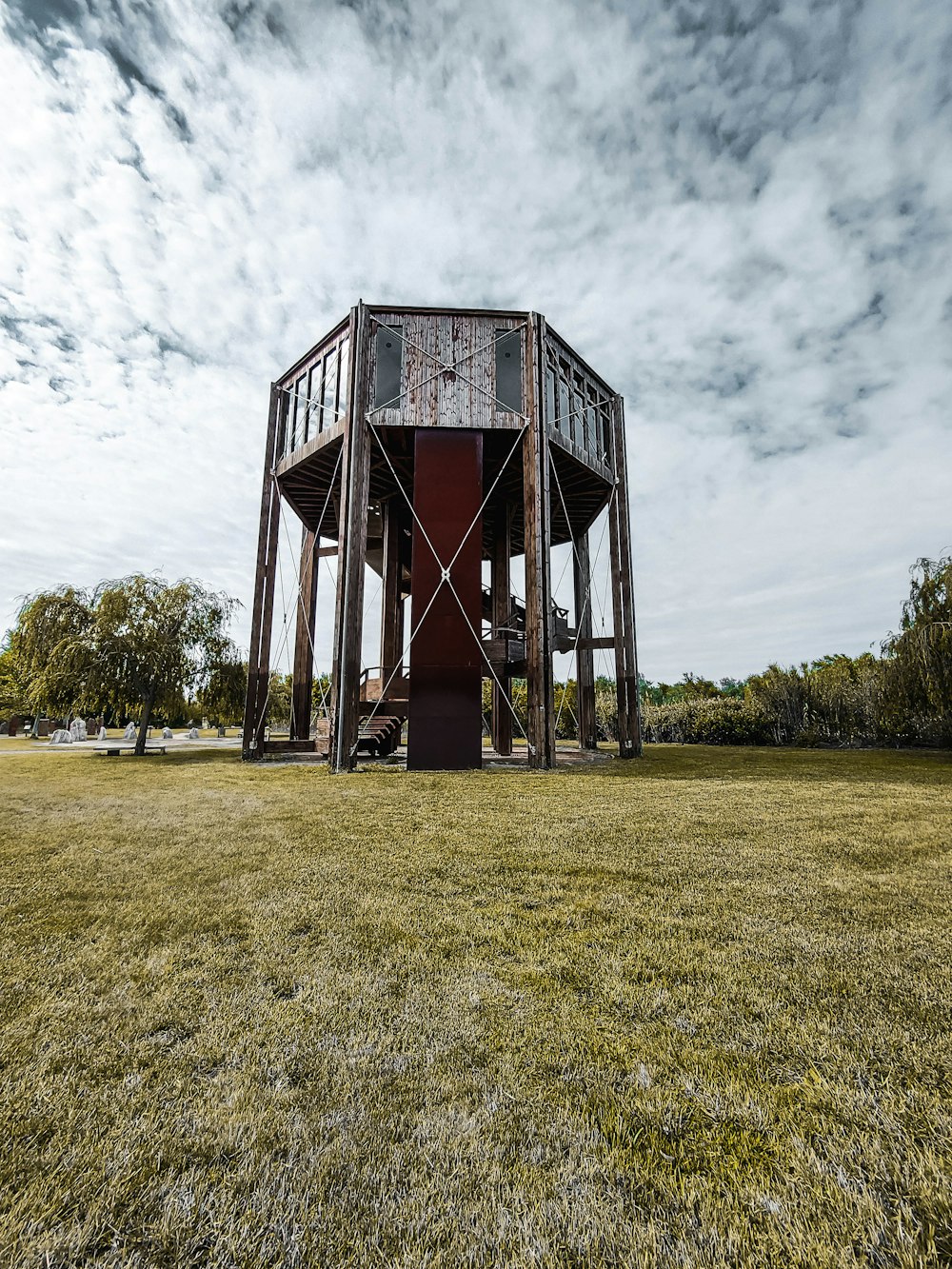 brown wooden building on green grass field under white clouds during daytime