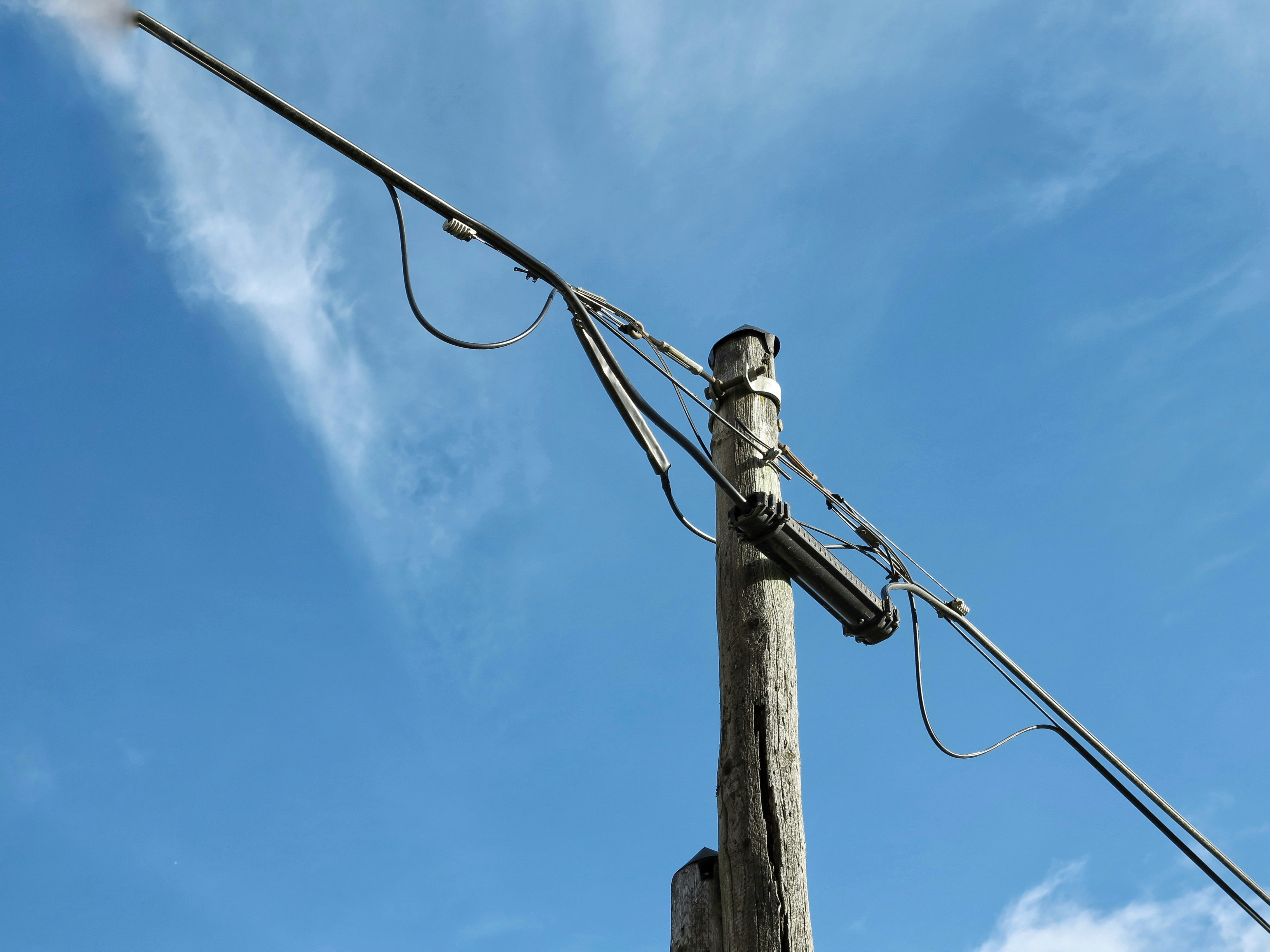 brown wooden electric post under blue sky during daytime