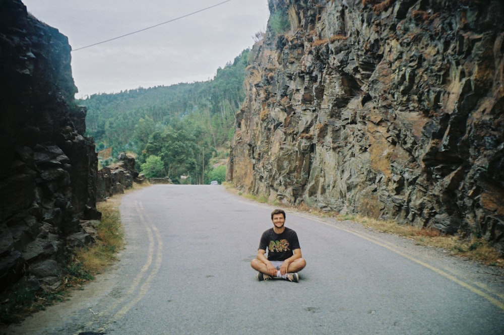 woman in black tank top sitting on gray concrete road during daytime