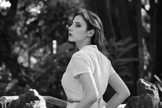 Portrait of a thoughtful woman in a natural setting with soft light and greenery.