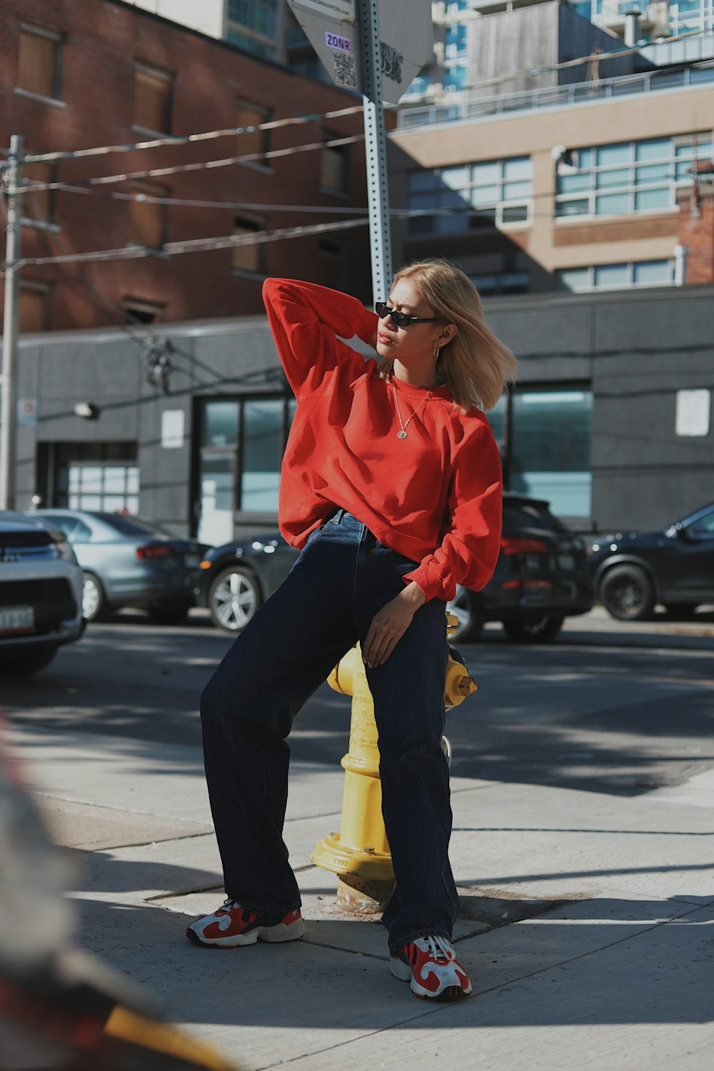Mujer con sudadera con capucha roja y pantalones negros caminando por la calle durante el día