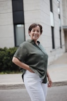 man in green button up t-shirt and white pants standing on road during daytime