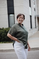 man in green button up t-shirt and white pants standing on road during daytime