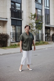 man in green polo shirt and white pants standing on road during daytime