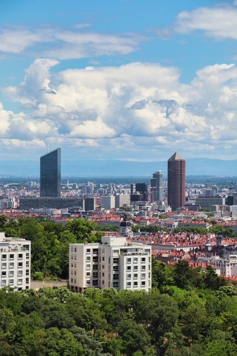 city buildings under blue sky and white clouds during daytime