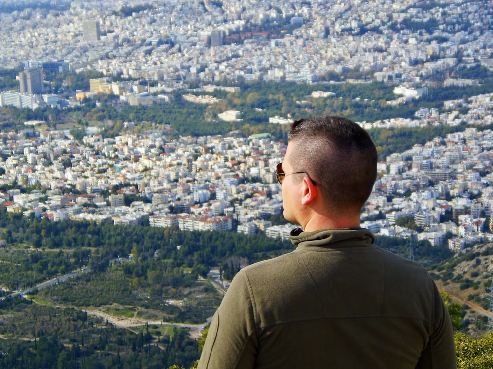 uomo in camicia verde che guarda gli edifici della città durante il giorno