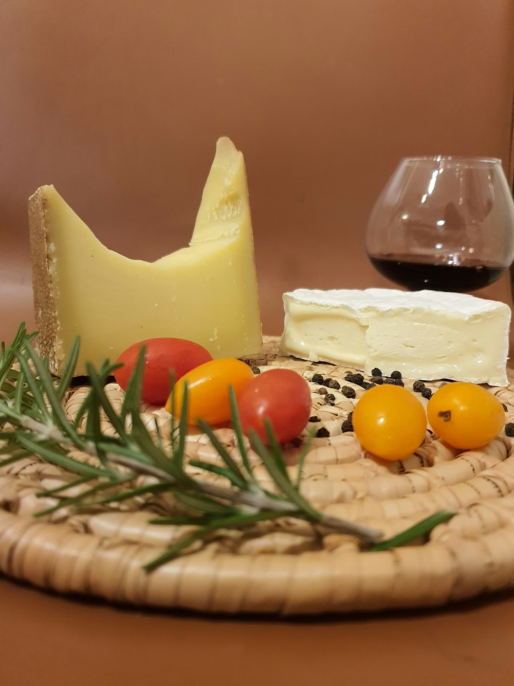 Queso con tomate y hojas verdes en canasta tejida marrón