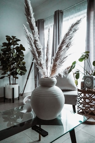 A cozy living room corner featuring pampas grass in a woven vase catching soft daylight.