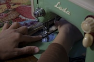 Artisan hands working on a sewing machine with colorful threads.