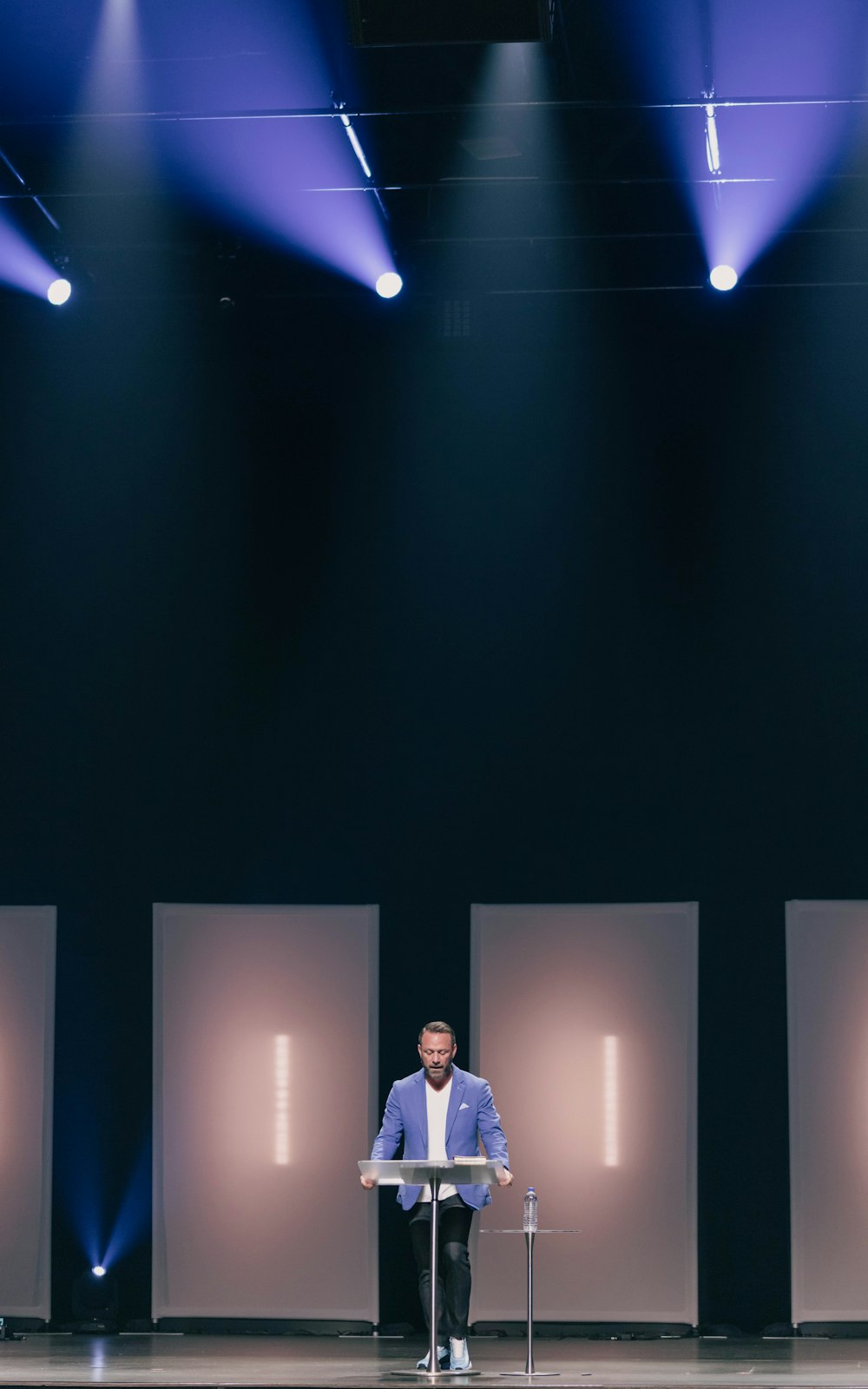 man in white suit standing on stage