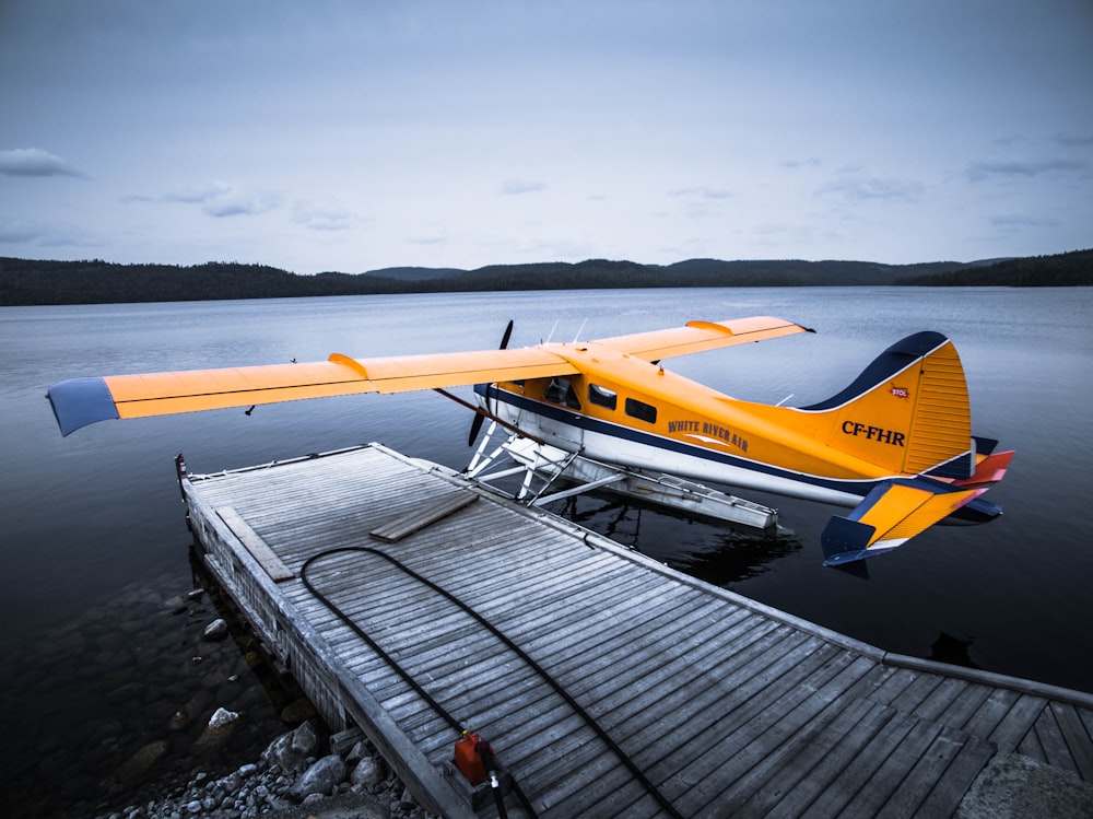 yellow and white plane on wooden dock during daytime