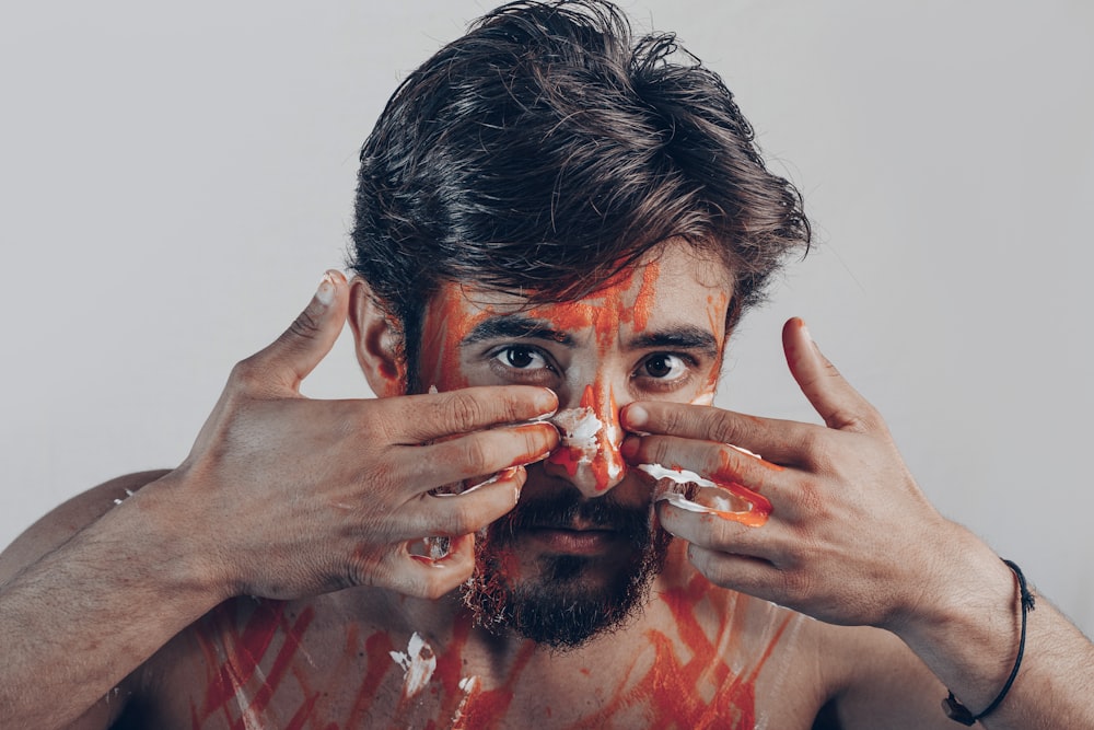 man in red crew neck shirt covering his face with hands