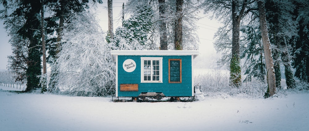 blue and white wooden house surrounded by snow covered trees during daytime