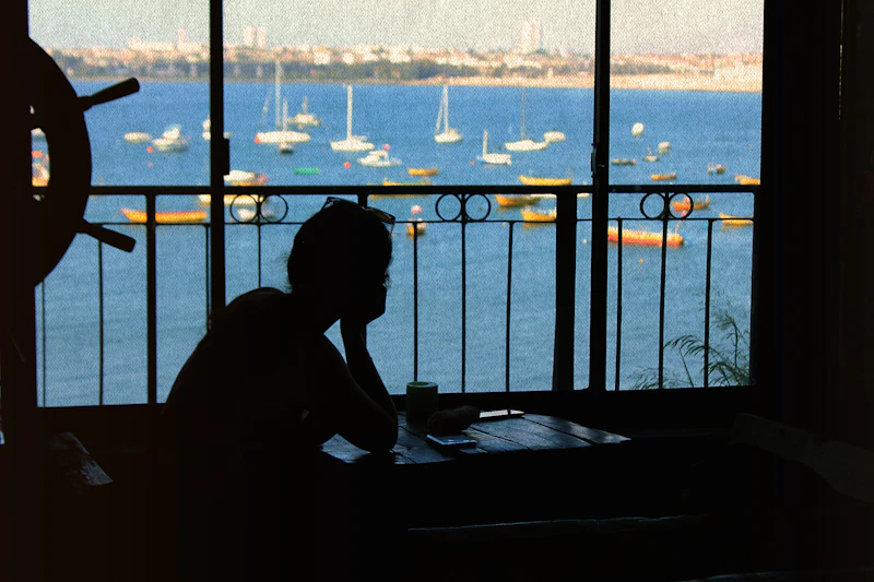 silhouette of woman sitting on bed near window during daytime