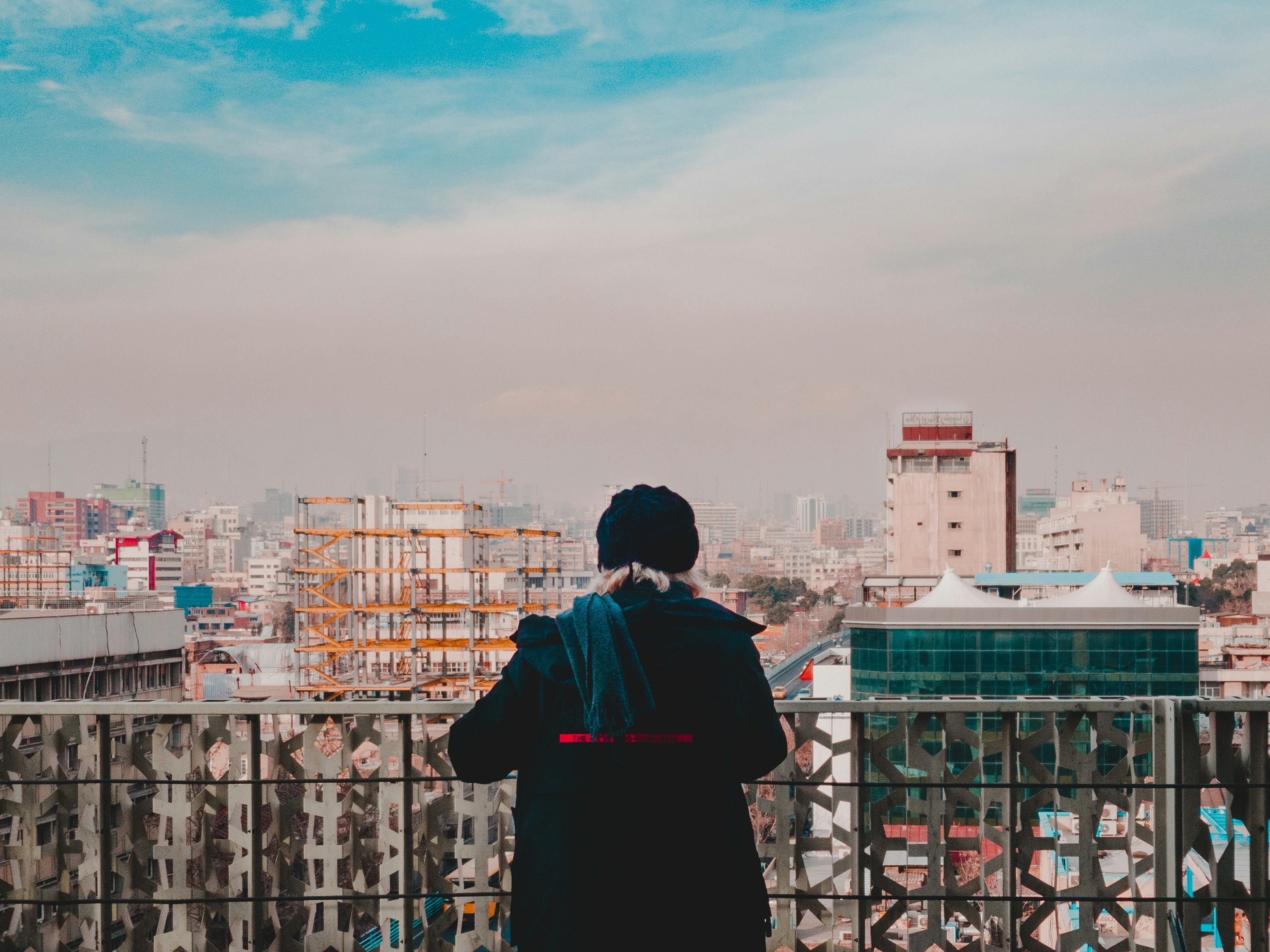 man in black and red shirt standing on top of building looking at city buildings during