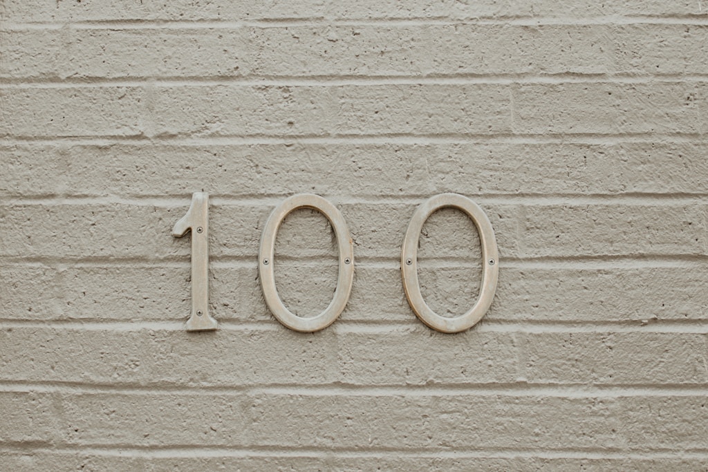 100 numbers on white wall with texture