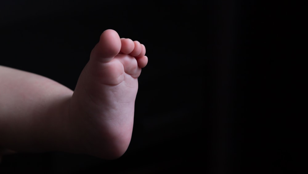 persons hand holding babys foot