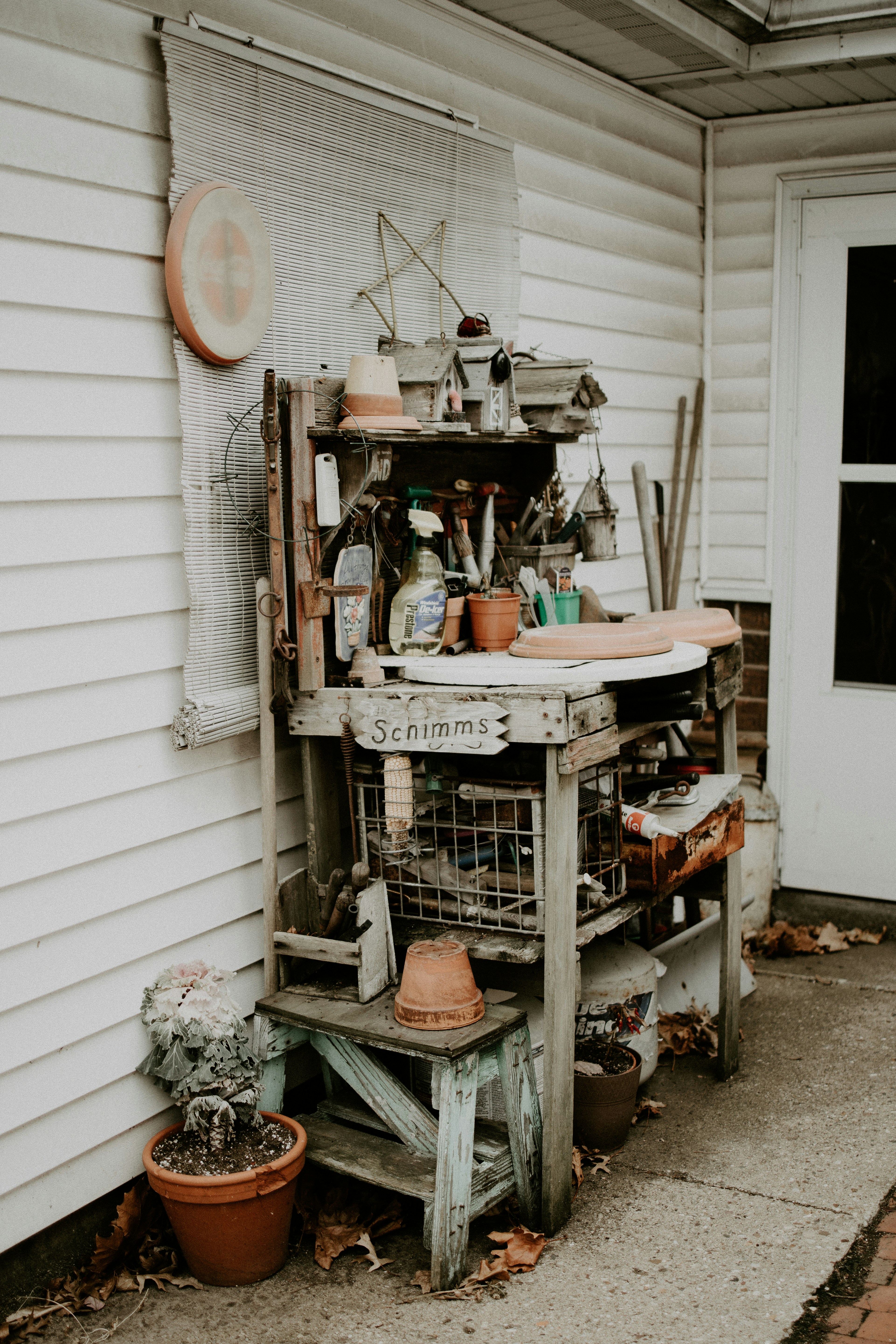 Outdoor wooden potting table with shelves in sunny garden, weathered cedar wood, plants and garden tools arranged on it