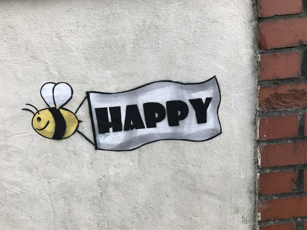 Un letrero que dice feliz con una abeja en él