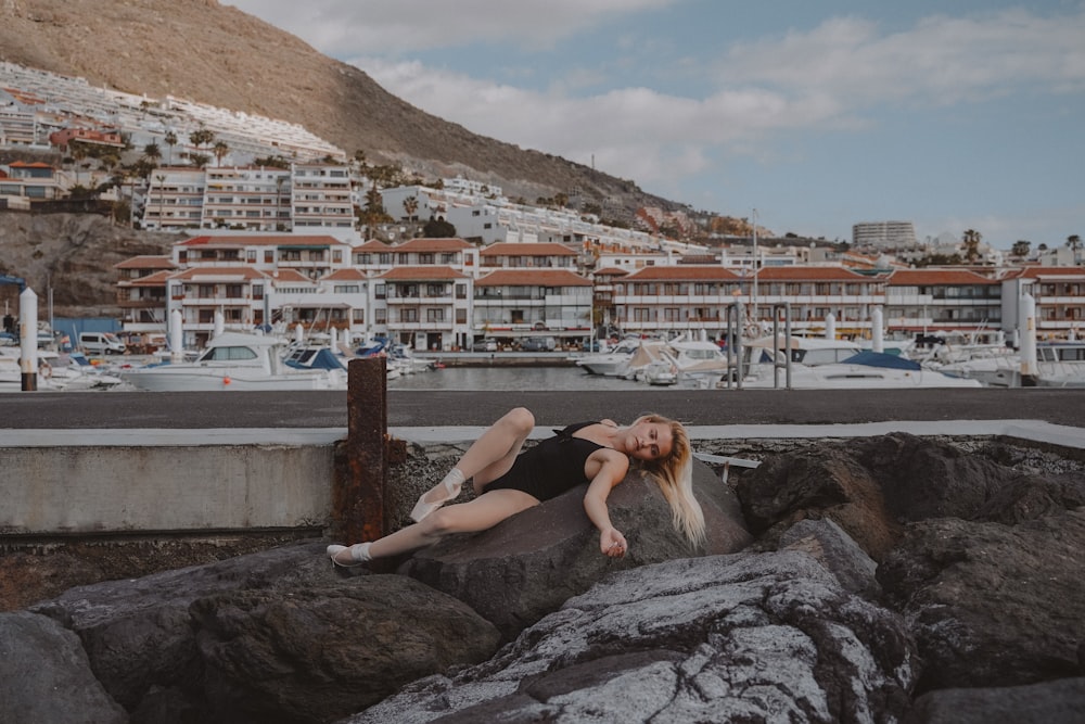 woman in black tank top sitting on rock