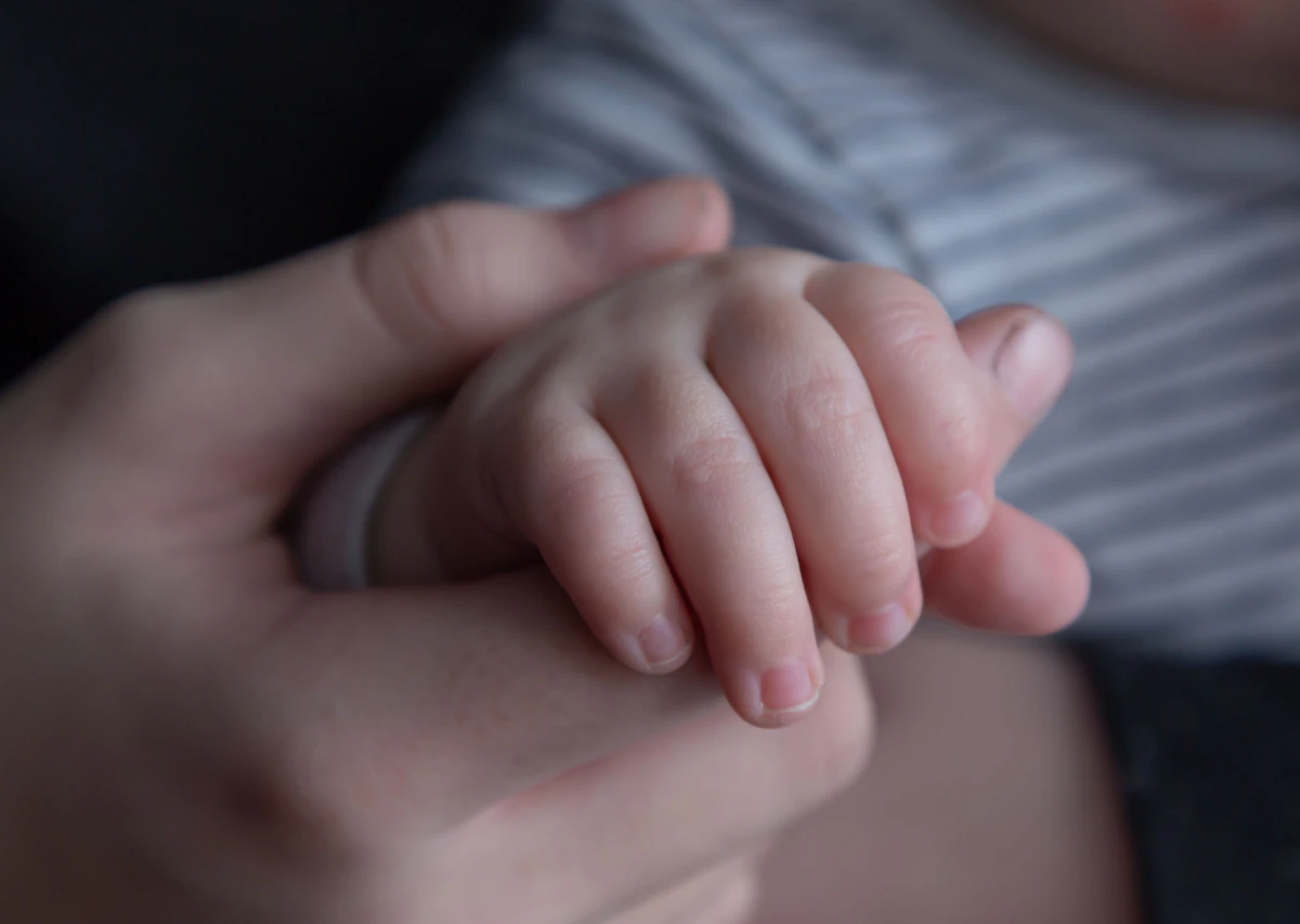 An adult's hand resting reassuringly over a child's hand