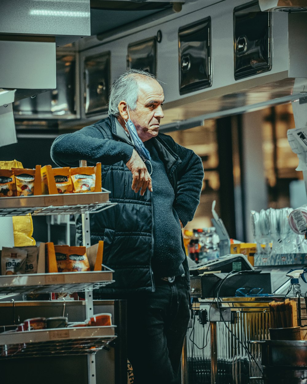 man in black leather jacket and blue denim jeans standing near food cart