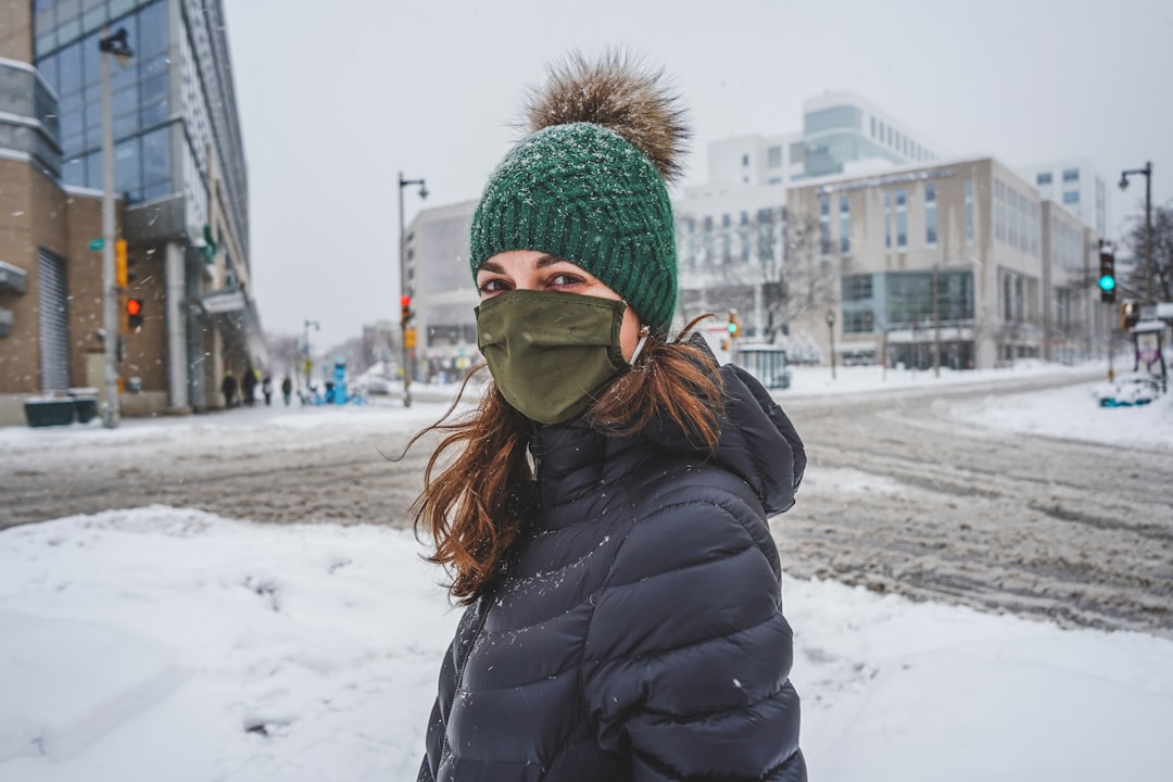 woman in black jacket and green knit cap standing on snow covered ground during daytime