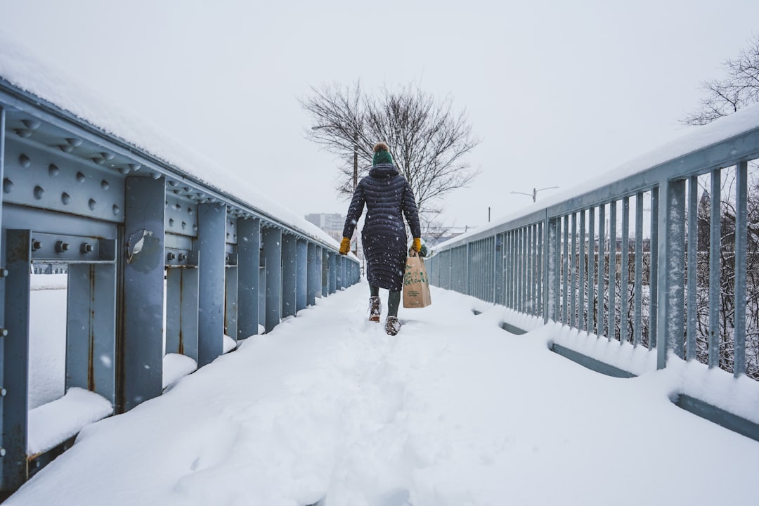 man in black jacket and black pants walking on snow covered pathway