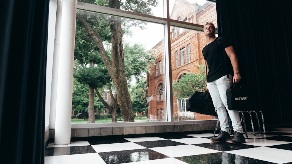 man in black shirt and white pants standing on white and black floor tiles