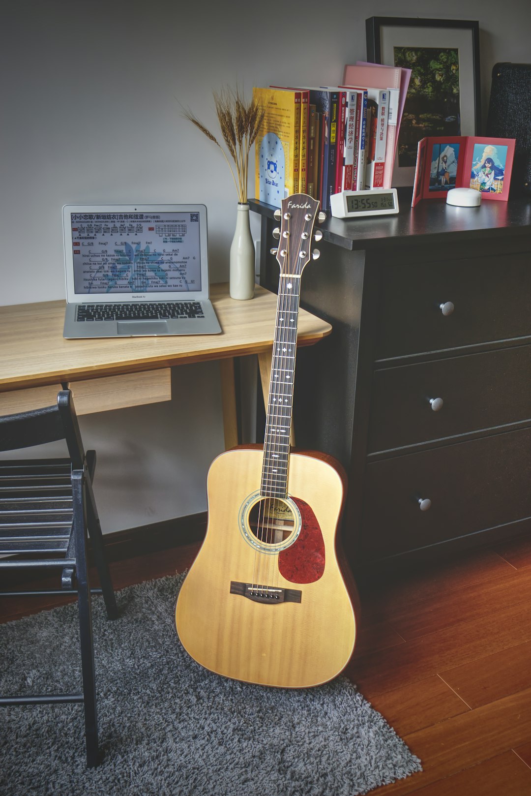 brown acoustic guitar beside black wooden drawer