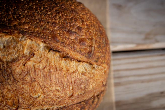 Close-up of a golden crusty sourdough loaf resting on a wooden board with flour dusted around