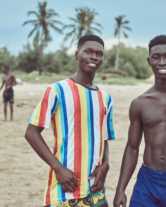 man in blue shorts standing beside man in white orange and blue stripe shirt in Sekondi-Takoradi Ghana