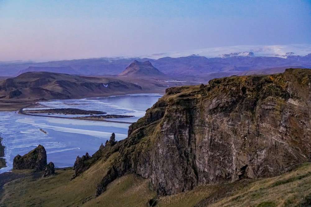 brown and green mountain beside body of water during daytime