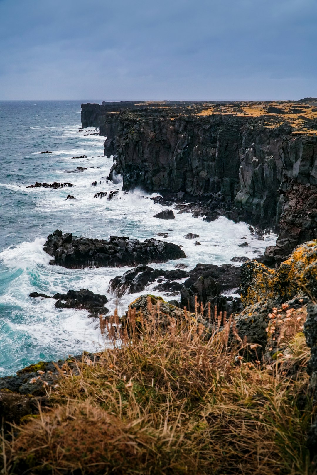 brown and green rock formation beside sea during daytime