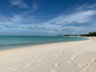 white sand beach under blue sky and white clouds during daytime