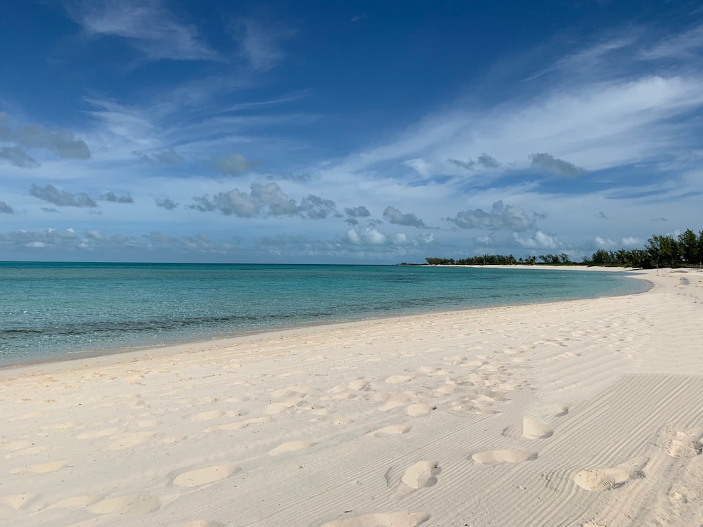 white sand beach under blue sky and white clouds during daytime