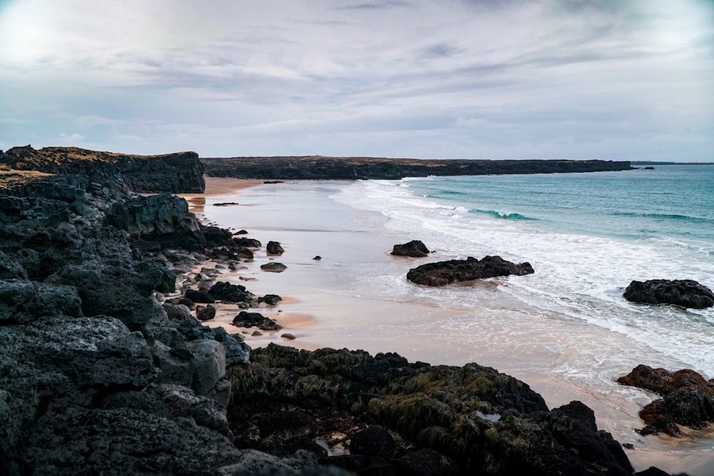 brown rock formation on sea under white clouds during daytime