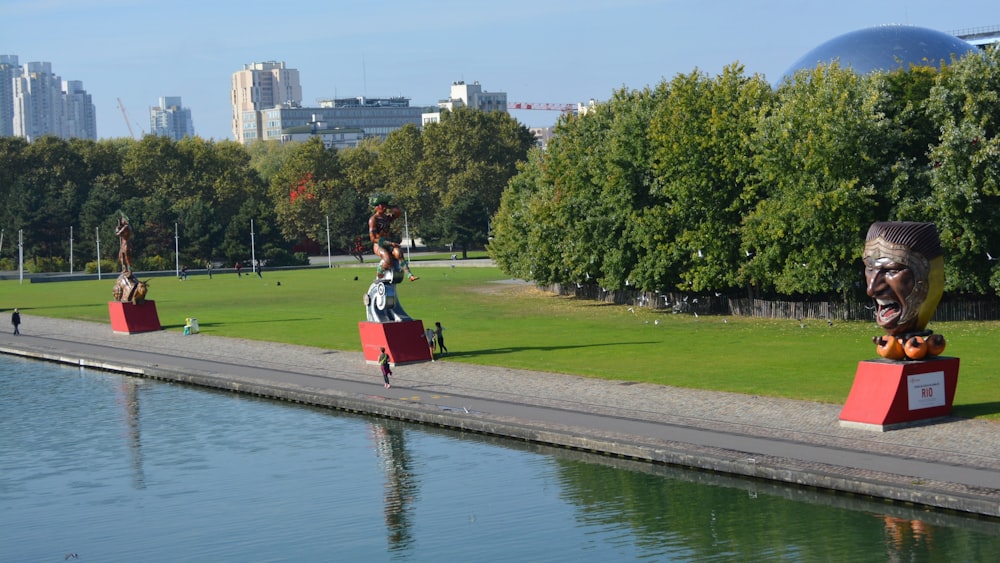 woman in red dress standing on gray concrete pathway near green grass field during daytime