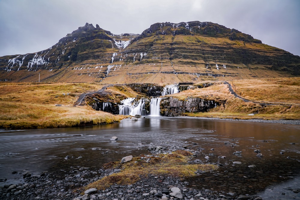 water falls in the middle of brown mountains