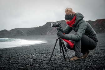 person in gray jacket and gray pants holding black dslr camera