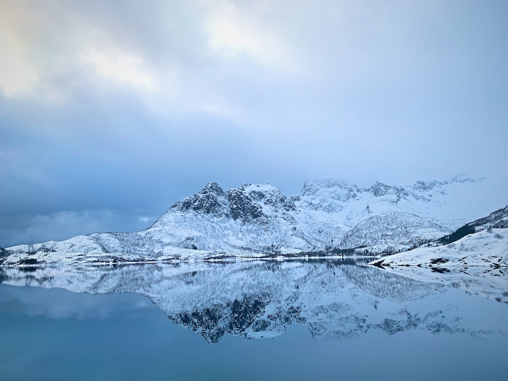 snow covered mountain near body of water during daytime