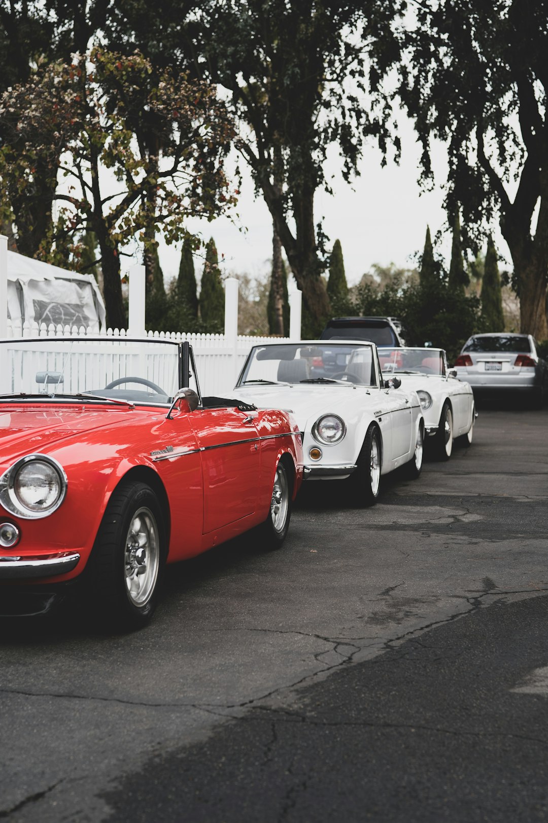 red and white convertible car parked on the street during daytime