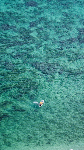 A vibrant turquoise jet ski cutting through the sparkling blue waters of Dar es Salaam under a clear sky.