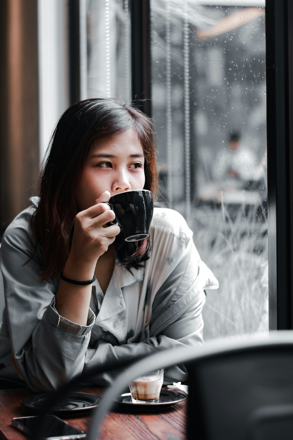 woman in white long sleeve shirt holding black ceramic mug