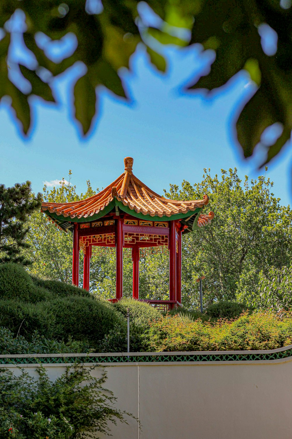 red and brown temple surrounded by green trees under blue sky during daytime