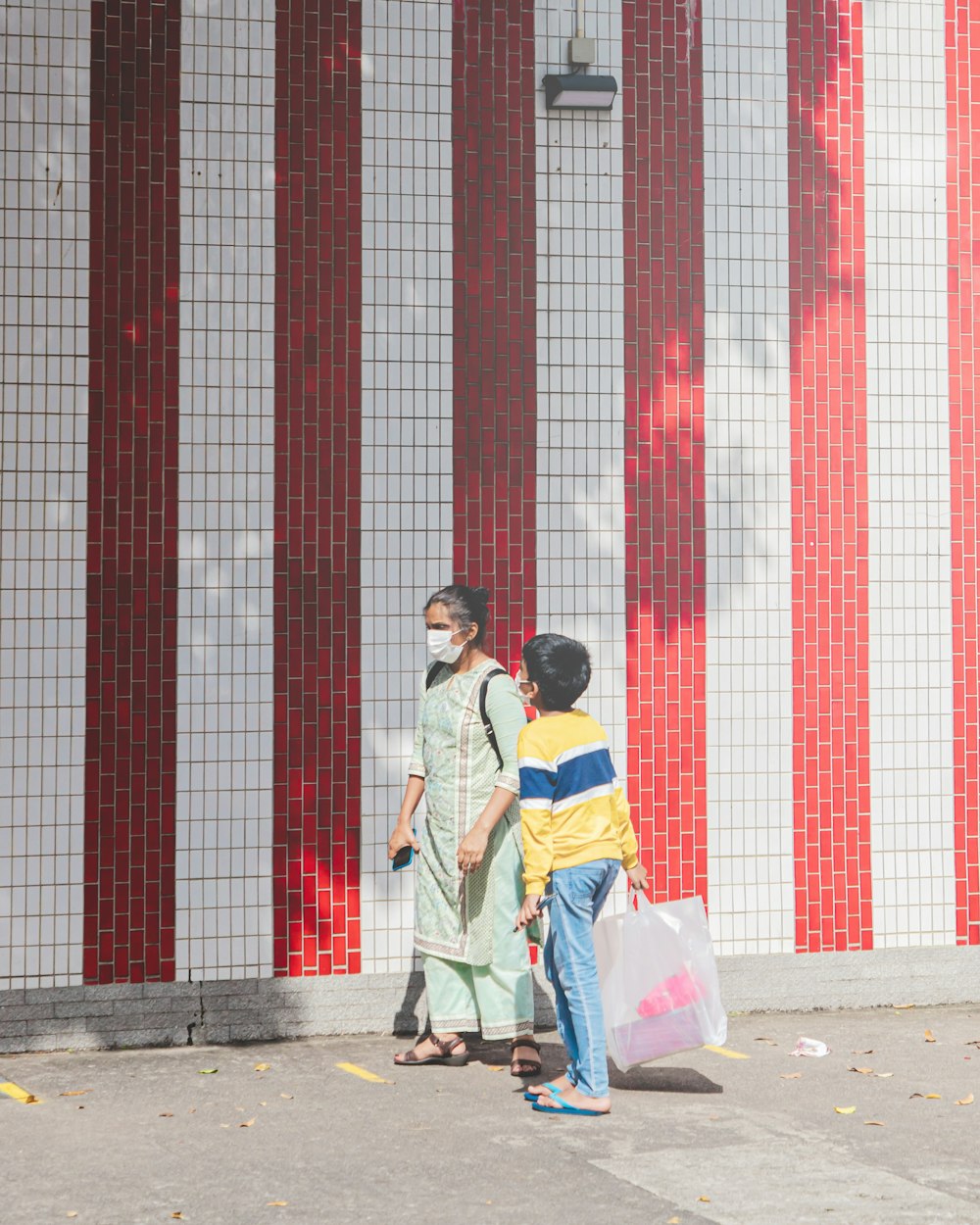 man and woman kissing near red and white wall during daytime