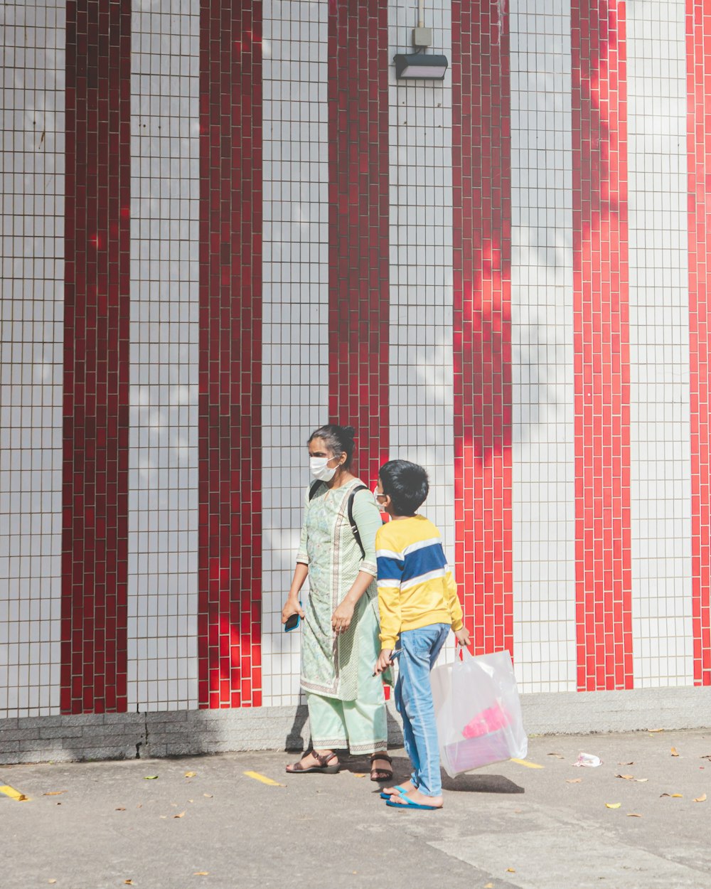 homem e mulher que se beijam perto da parede vermelha e branca durante o dia