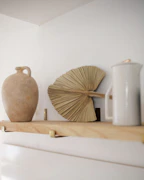 Elegant ceramic vases in neutral tones displayed on a minimalist wooden shelf